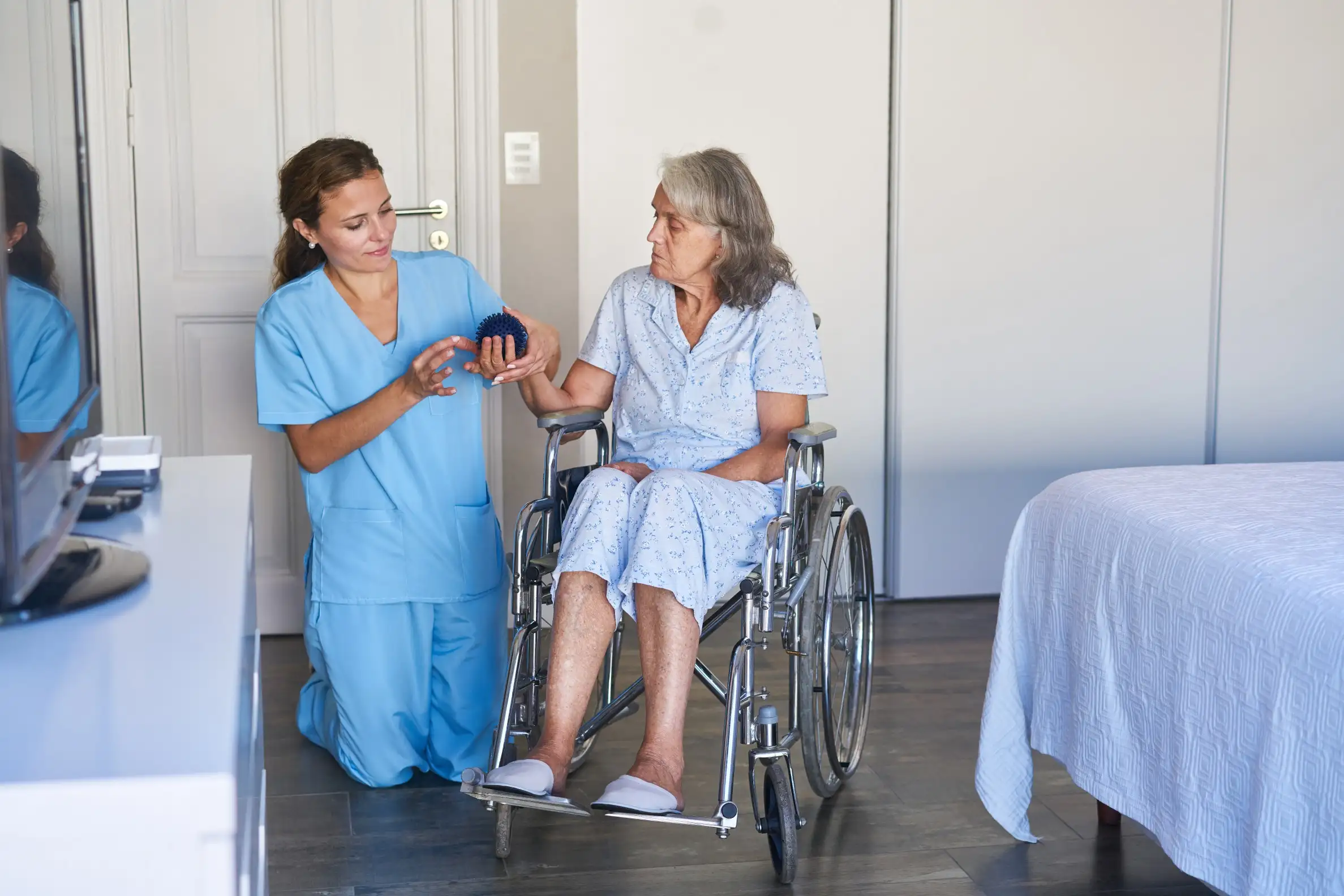 Nurse showing a therapy ball to an elderly woman in a wheelchair