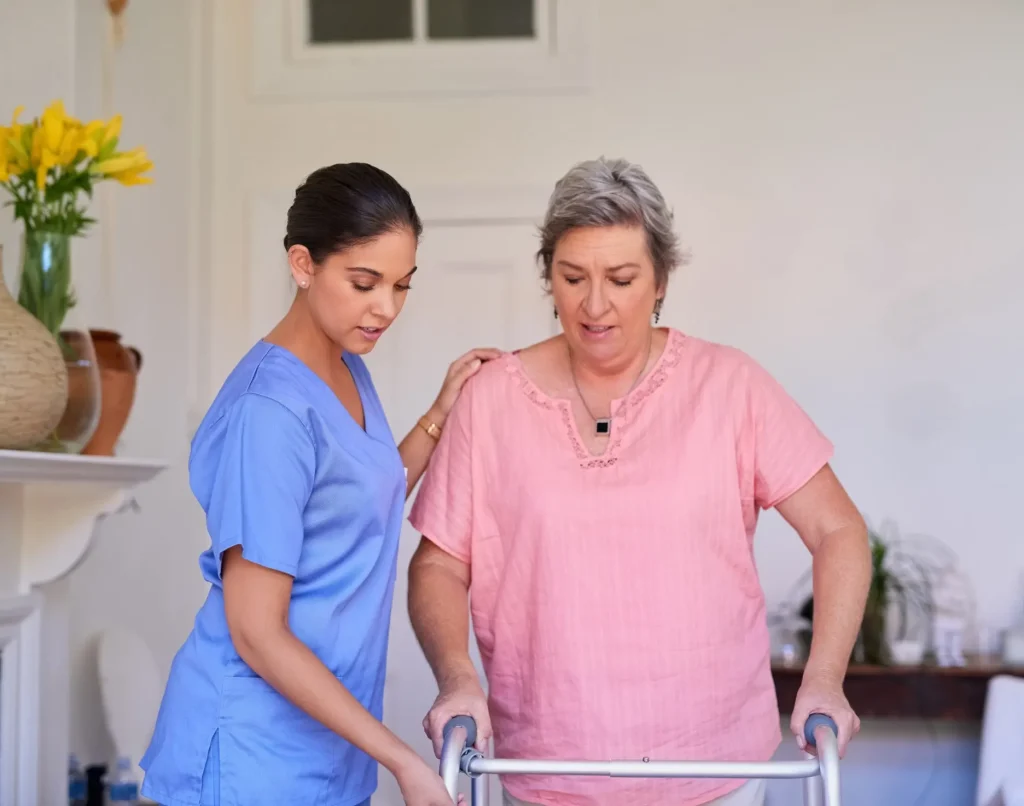 Nurse helping an older woman walk with a mobility walker