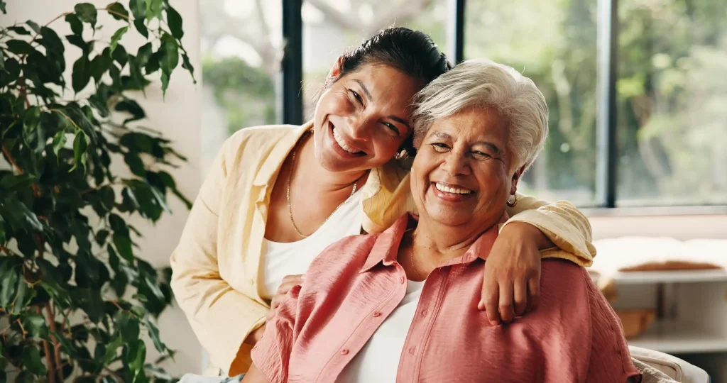 Younger woman hugging an older woman, both smiling