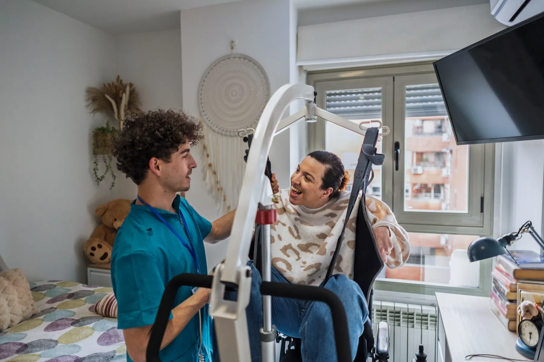 Caregiver assisting a woman using a patient hoist lift